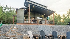 Une cabane moderne dotée d’une terrasse, d’un espace salon extérieur et d’un mur de soutènement en pierre.