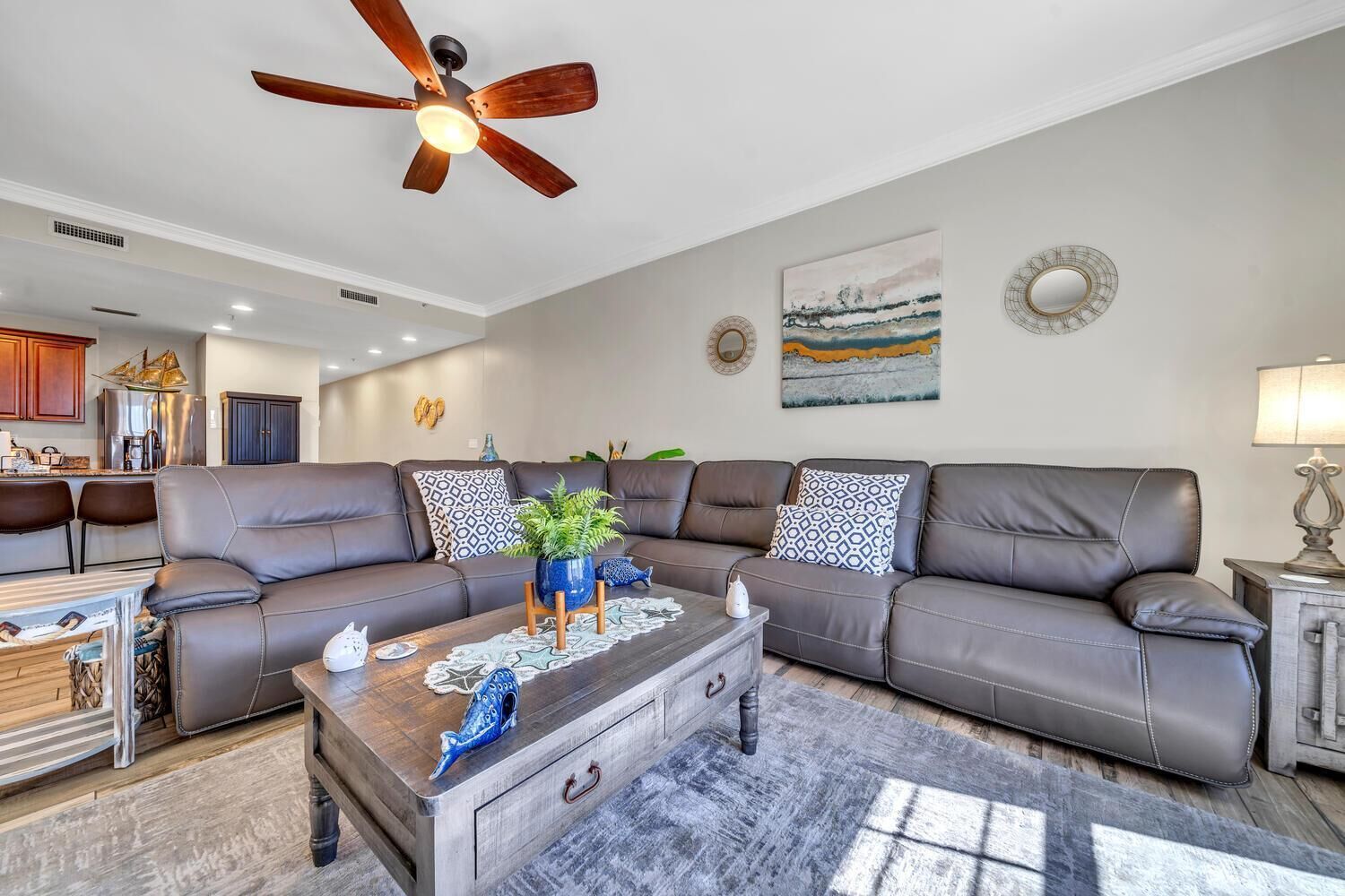 A modern living room with a sectional sofa, a wooden coffee table, and a ceiling fan.