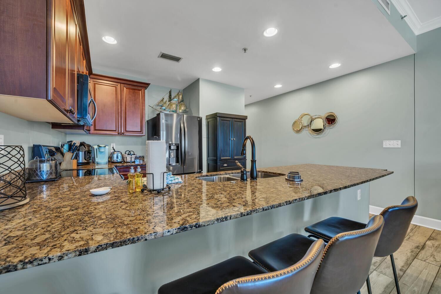 Eine moderne Küche mit Granit Arbeitsplatten, Edelstahlgeräten und einer Bar mit Ledersitzen.
