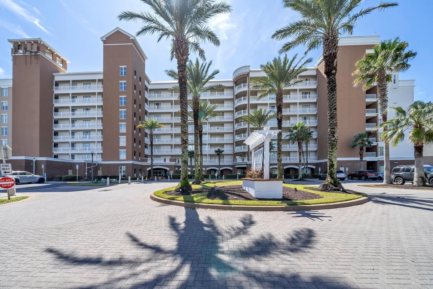 A multi-story hotel with a central courtyard featuring palm trees and a white sculpture.