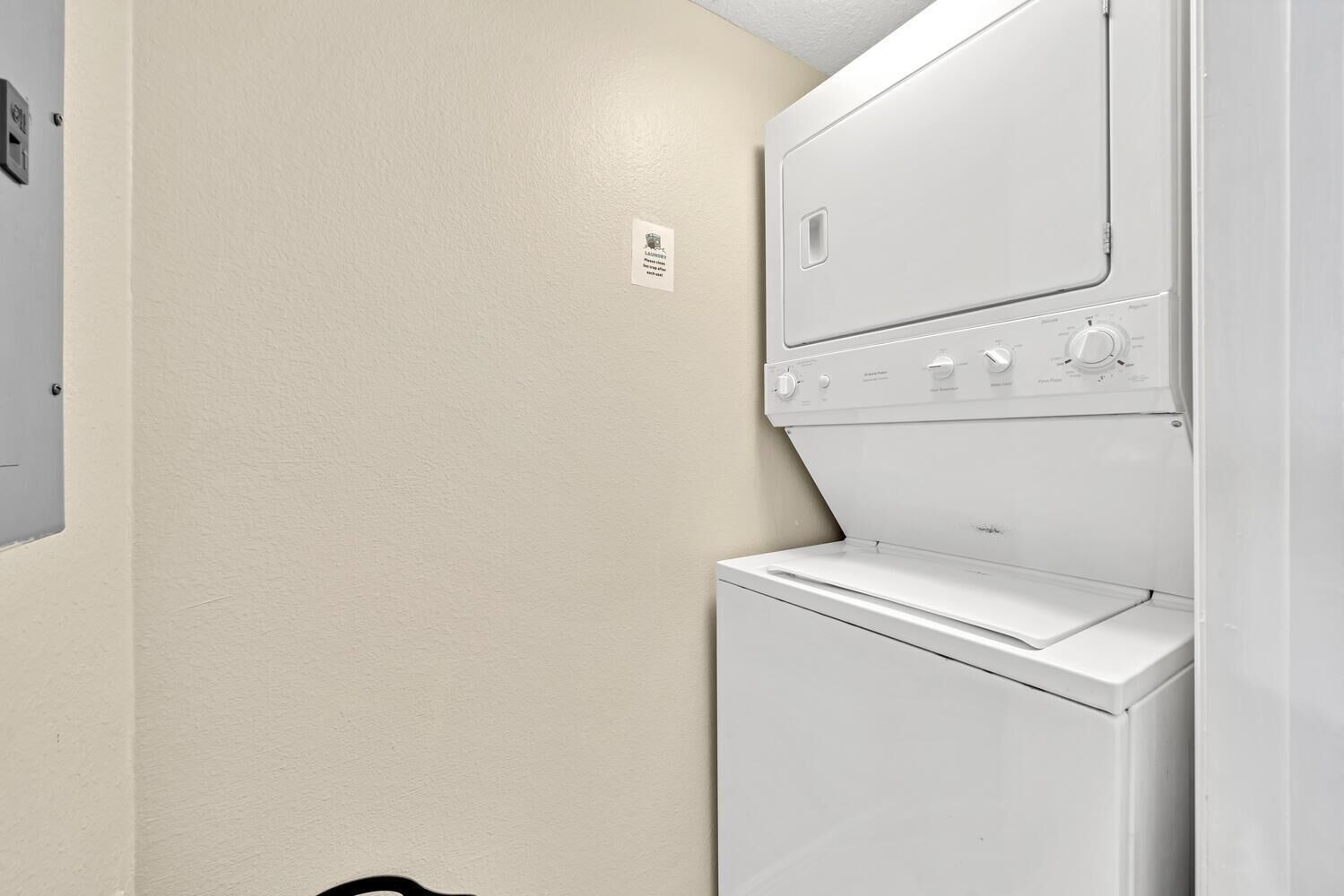 A laundry room with a white washing machine and dryer stacked on top of each other.