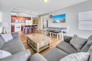 A modern living room with a wooden coffee table, grey sofas, and a dining area with a bench. - Laketown Wharf 801 (Panama City Beach)