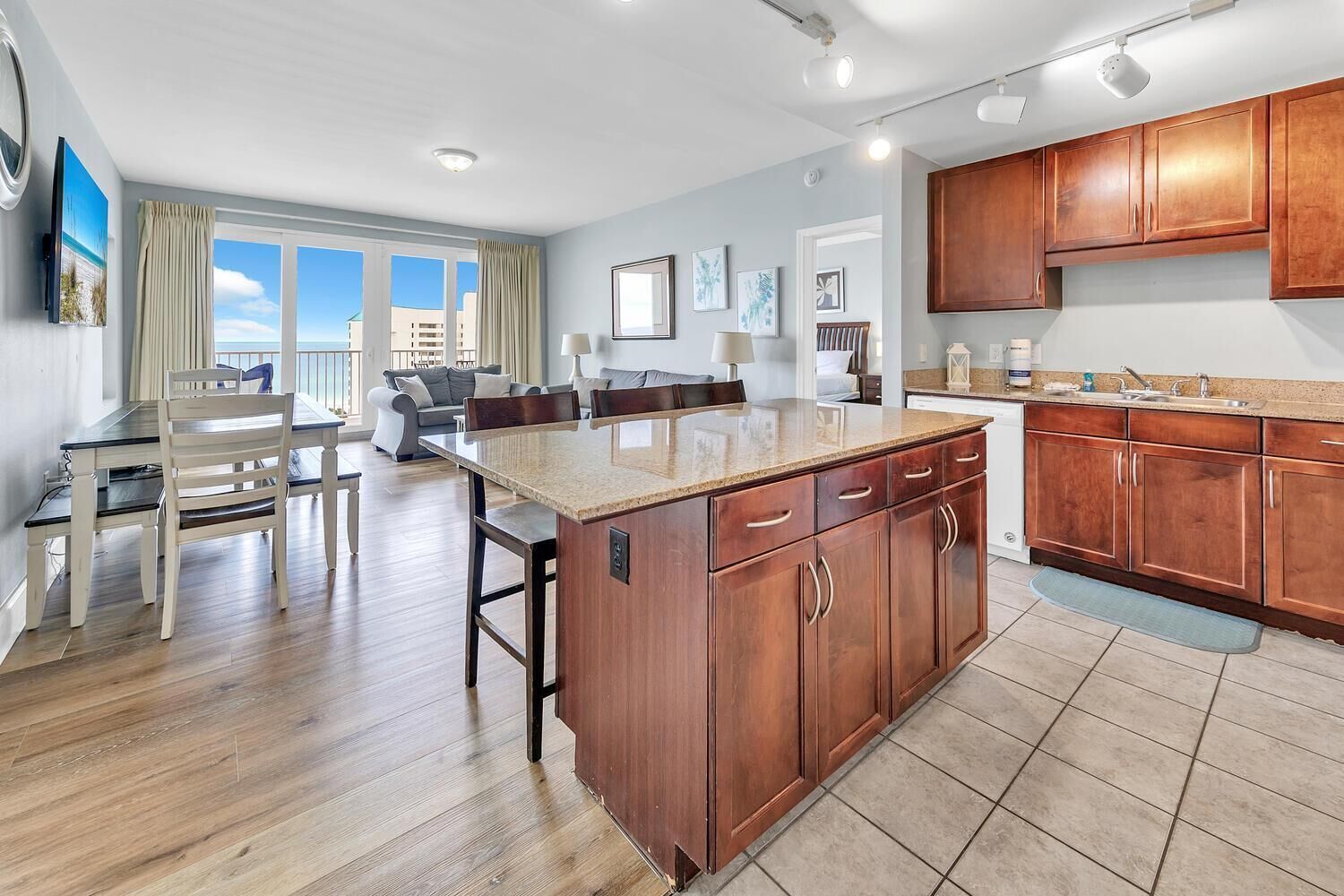 A modern kitchen with wooden cabinets, a granite countertop, and a dining area with a table and chairs.