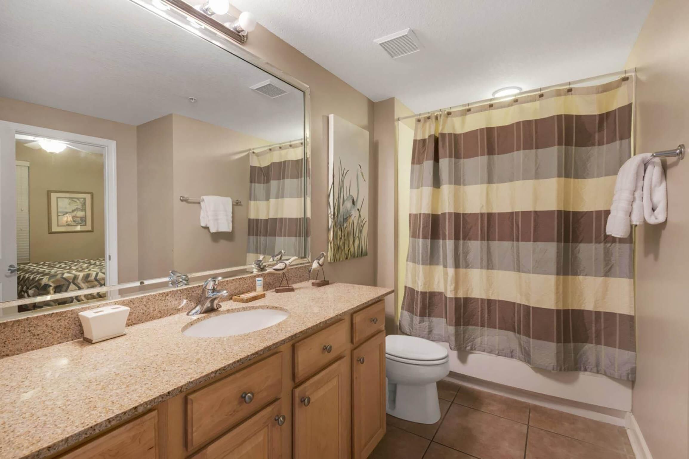 A bathroom with a sink, mirror, and shower curtain.