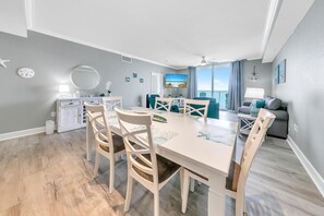 A modern living room with a dining area, a sofa, and a view of the ocean. - Tidewater 2308 (Panama City Beach)