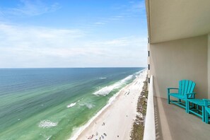 A balcony with turquoise chairs overlooking a beach with waves and a clear sky. - Tidewater 2308 (Panama City Beach)