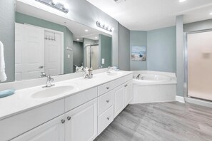 A modern bathroom with a double sink vanity, a large mirror, a bathtub, and a shower enclosure. - Tidewater 2308 (Panama City Beach)
