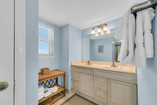 Bathroom features a double vanity with a large mirror and a towel rack.
