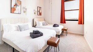Ein Hotelzimmer mit zwei Betten, einem kleinen Tisch und Blick auf die Stadt.