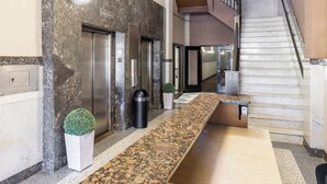 Eine moderne Lobby mit einer Marmor-Rezeption, einer Treppe und Aufzügen.