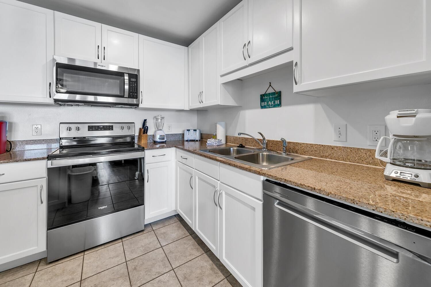 A modern kitchen with white cabinets, stainless steel appliances, and a granite countertop.