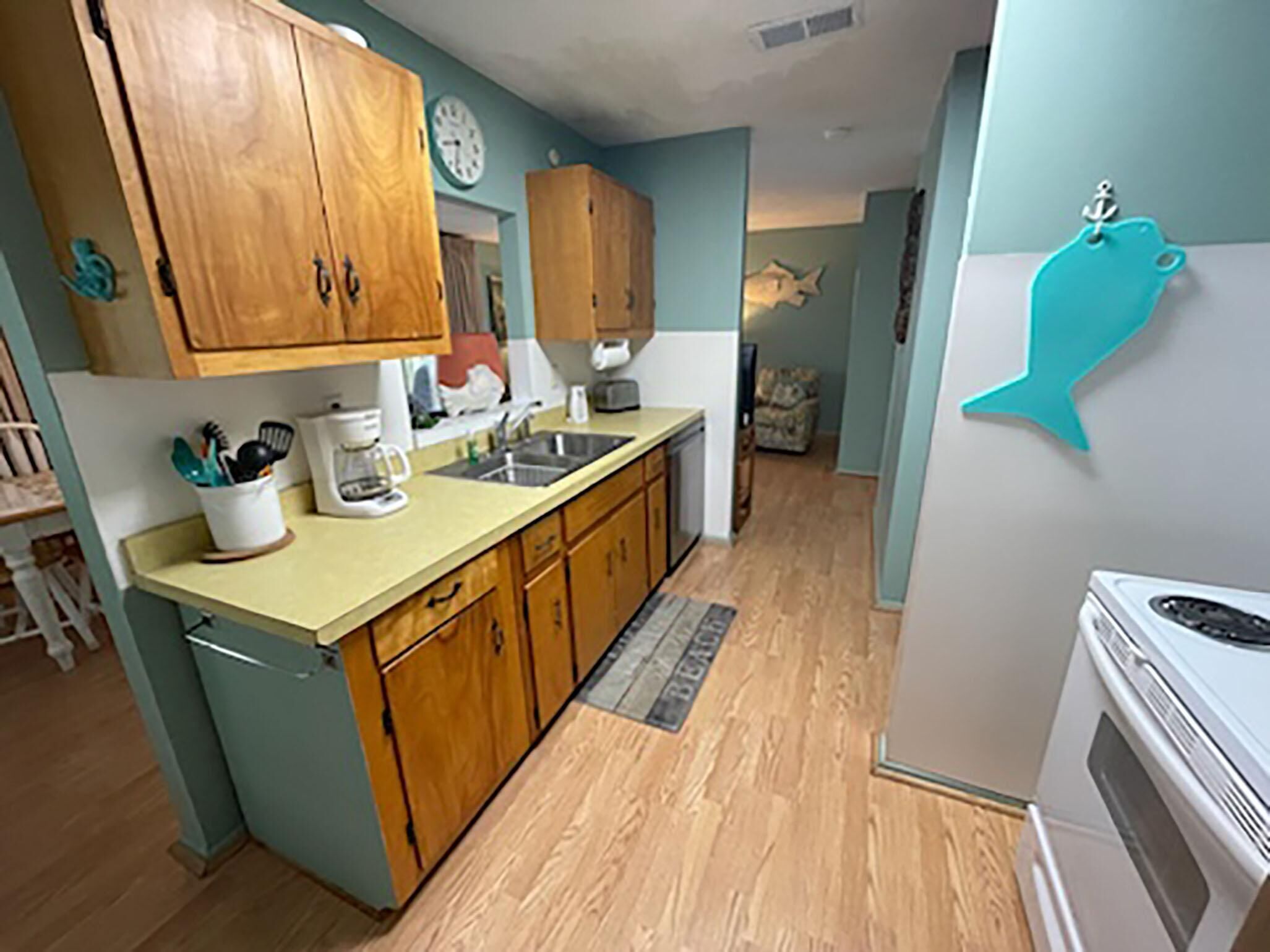 A kitchen with wooden cabinets, a sink, a coffee maker, and a refrigerator.
