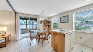 Eine Küche mit Esstisch, Stühlen, einem Holzschrank und einem Fenster mit Jalousien.