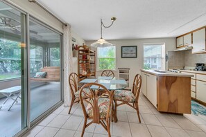 A modern kitchen with a glass dining area, wooden chairs, and a view of the outdoors. - Beach Haven (Panama City Beach)