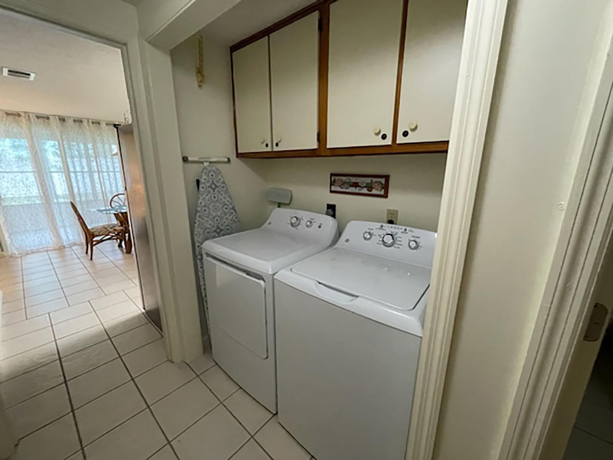A laundry room with two washing machines, a drying rack, and a dining area with a table and chairs.