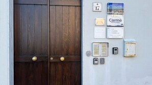 Eine Holztür mit Messingklinke, ein an der Wand befestigter Briefkasten, ein Klingelknopf, ein Gegensprechanlage und eine Schild mit der Nummer 17.