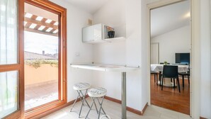 A compact kitchen with a built-in microwave, two stools, and a small table.