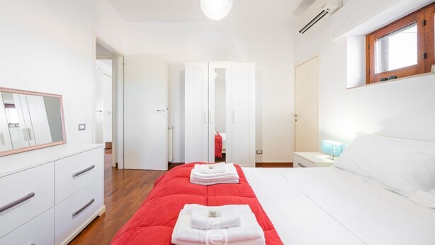 A bedroom with a bed, a dresser, a mirror, a window, and a door.