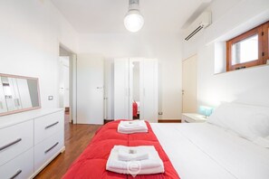 Une chambre à coucher avec un lit, une commode, un miroir, une fenêtre et une porte.