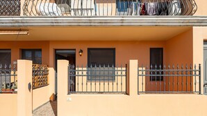 A residential building with a gated entrance, a balcony with clothes hanging, and a small window. - Dahlia Apartment (Cabras)