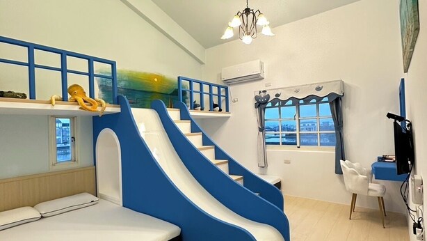 A room with a bunk bed, a blue and white slide, a desk with a chair, and a window with a view. - Ians Home (Dongshan)