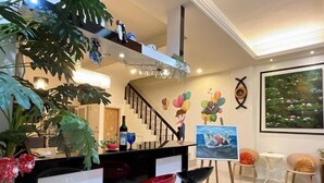 A modern interior with a staircase, a dining area with bar stools, and a painting of a beach scene. - Ians Home (Dongshan)