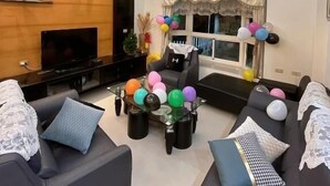 A modern living room with a TV, sofas, a glass coffee table, and a chandelier. - Ians Home (Dongshan)