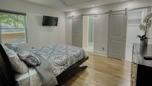 Ein modernes Schlafzimmer mit Bett, Fernseher, Deckenventilator und Schiebetürenschrank.