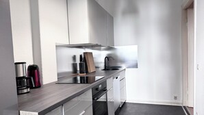 Ett modernt kök med en köksfläkt i rostfritt stål, en kaffebryggare och ett knivställ.