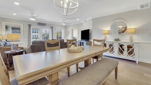 A spacious dining area with a long wooden table, cushioned benches, and a chandelier.