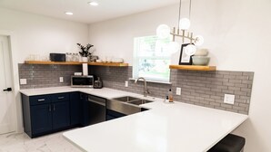 A modern kitchen with a large island, dark blue cabinets, and a white countertop. - New and Modern Double En-Suite (Pensacola)