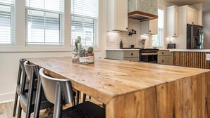 A modern kitchen with a wooden dining table, chairs, and a backsplash. - The Cowboy (Southern Pines)