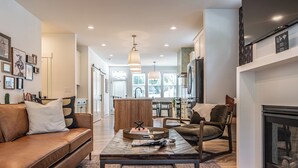A modern living room with a leather sofa, a coffee table, and a fireplace. - The Cowboy (Southern Pines)