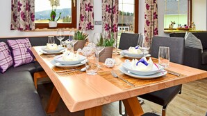 A dining table set with plates, glasses, and cutlery, flanked by sofas and a window with curtains. - Beautiful home in Mariapfarr with WiFi (Mariapfarr)