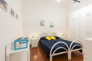 A bedroom with a bed, nightstands, a wardrobe, and wall art.