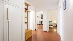 Un couloir avec des armoires blanches, une armoire en bois et une petite table avec une chaise.