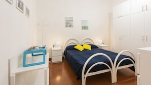 Une chambre à coucher comprenant un lit, des tables de chevet, une armoire et des œuvres d’art murales.