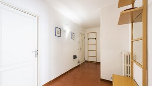 Un couloir avec une porte blanche, un radiateur et une échelle en bois.