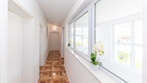 A hallway with wooden flooring, white walls, and large windows with white flowers. - 1 bedroom nice apartment in Kastel Kambelovac (Kastel Kambelovac)
