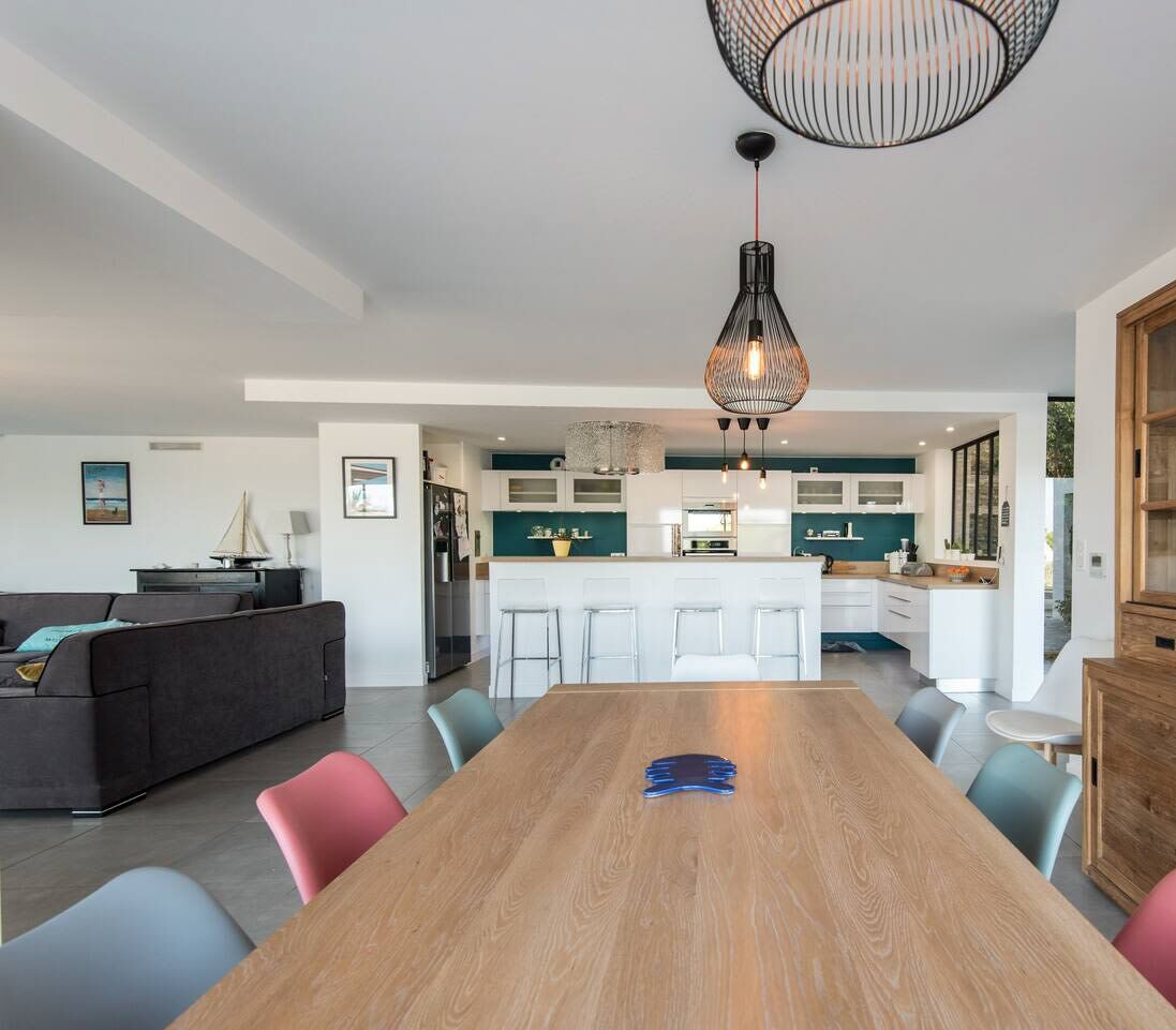 A modern kitchen with white cabinets, a central island, and a hanging light fixture.