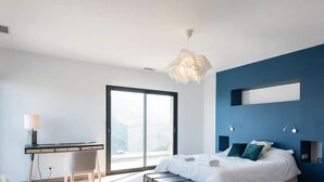 Ein modernes Schlafzimmer mit Bett, Schreibtisch und großem Fenster.
