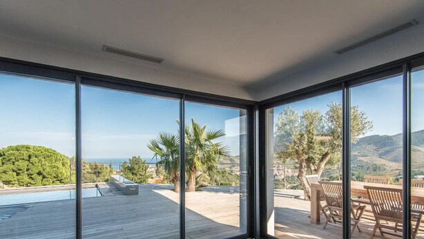 Ein modernes Interieur mit großen Fenstern, einem Holzterrasse und einem Pool.