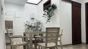 Un comedor con una mesa, sillas, un calentador de agua y una ventana con una planta.