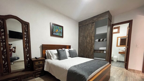 Un dormitorio con una cama grande, un armario, un espejo y un cuadro en la pared.