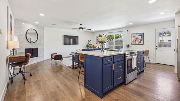 A spacious kitchen with a central island, a dining area with a table and chairs, and a living area with a sofa and a TV. - Feel at Home! New Renovated House By *Grandscapes* (The Colony)