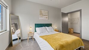 Une chambre moderne avec un lit, des lampes de chevet, un ventilateur de plafond, un miroir et une porte donnant sur un placard.