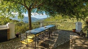 An outdoor patio with a table and chairs, surrounded by a stone-tiled floor and a metal fence. - Cortijo Entre Sierras Carcabuey by Ruralidays (Córdoba)
