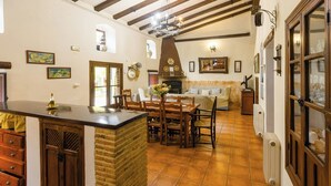 A cozy kitchen with a central island, wooden chairs, a fireplace, and a dining table. - Cortijo Entre Sierras Carcabuey by Ruralidays (Córdoba)