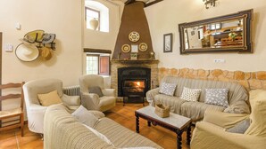A cozy living room with a fireplace, striped sofas, and a wooden coffee table. - Cortijo Entre Sierras Carcabuey by Ruralidays (Córdoba)