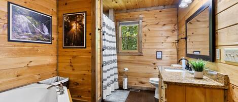 Une salle de bain rustique, avec une baignoire, un lavabo et une fenêtre.